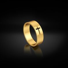 a gold ring with a cross on the side and a reflection in the dark background