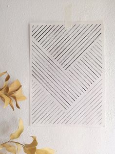 a piece of paper that has been cut into squares and placed on a wall next to some flowers