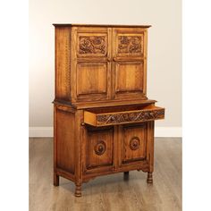 an old wooden cabinet with carvings on the front and drawers, sitting on a hard wood floor