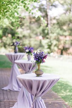 the tables are covered with purple tablecloths and vases filled with flowers on them