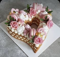 a heart shaped cake decorated with pink flowers and icing on a white paper towel