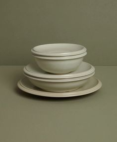 three white plates stacked on top of each other in front of a gray wall and floor