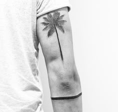 a man's arm with a palm tree tattoo on the left side of his arm