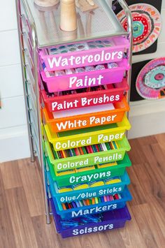 a stack of colored pencils sitting on top of a wooden floor next to a wall