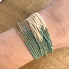 a person's arm with several bracelets on top of it, one is green and the other is white