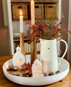 a white coffee cup sitting on top of a wooden table next to a vase filled with flowers