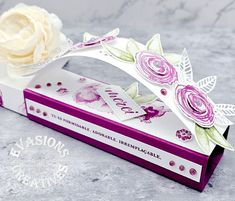 a white rose sitting on top of a purple box