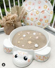 a white bowl filled with sand sitting on top of a table next to a vase