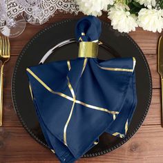 a black plate with a blue and gold napkin on it next to some silverware