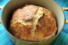 a loaf of bread in a pot on a blue and yellow table cloth with a spoon