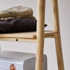 a white suitcase sitting on top of a wooden chair next to a brown and black pillow