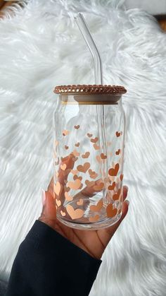 a hand holding a glass with gold confetti on the rim and a straw in it