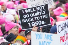 a group of people holding up signs in the middle of a crowd with pink turbans