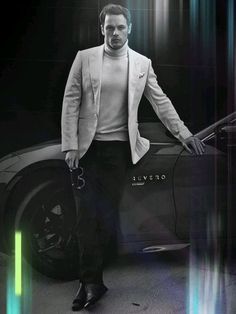 a man standing next to a car in front of a black and white background with neon lights