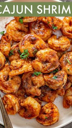 a white plate topped with cooked shrimp and garnished with parsley next to a fork