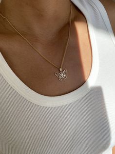 a woman wearing a necklace with a butterfly on it