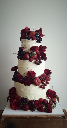 a three tiered cake with berries and flowers on top