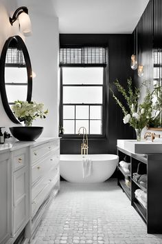 a white bath tub sitting next to a large mirror in a bathroom under a window