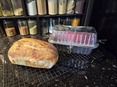 a loaf of bread sitting on top of a metal rack next to a container filled with food