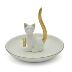 a cat figurine sitting on top of a white plate with gold trimming