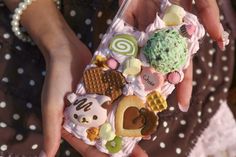 a person holding a cell phone case with various candies on it and an ice cream cone in the middle