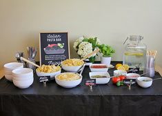 a table topped with lots of different bowls and containers filled with food next to a sign that says italian pasta bar