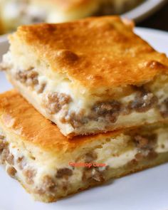 two pieces of cheese and meat pie on a plate with another piece in the background