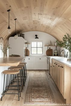 a kitchen with wooden floors and white walls, along with stools on the counter