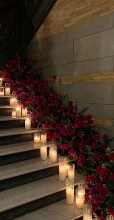 candles are lined up on the steps with red flowers