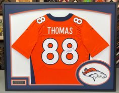 an orange jersey is on display in front of a framed photo with the name and number