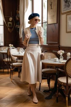 a woman standing in front of a table wearing a hat and dress with stripes on it