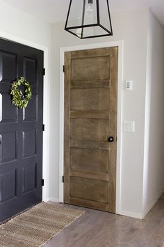 a door with a wreath hanging on it next to a light fixture and wooden floor