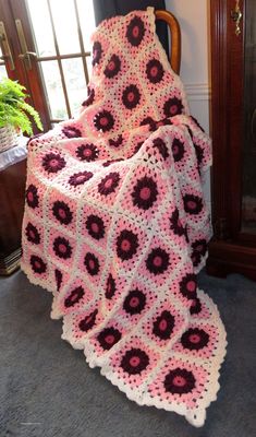 a crocheted blanket sitting on top of a chair in front of a window