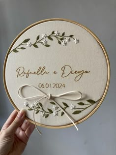 a hand holding up a wedding coaster with flowers and leaves on the front, which reads raftilla dege