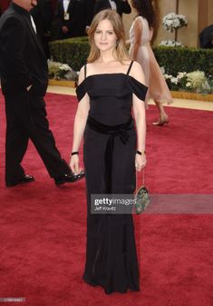 the actress in an off - shoulder black gown poses on the red carpet at the oscars