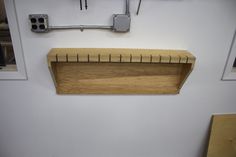 a wooden shelf sitting on the side of a white wall next to a pair of scissors