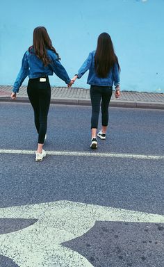 two girls walking down the street holding hands