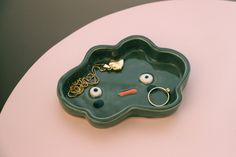 a green tray that has some rings and other items in it on top of a table