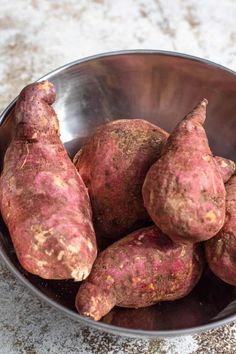 a metal bowl filled with sweet potatoes on top of a counter