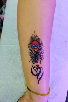 a woman's arm with a tattoo on it and a peacock feather in the middle