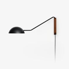 a wall lamp with a wooden arm and black shade on the side, against a white background