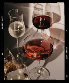 three wine glasses filled with different colored wines