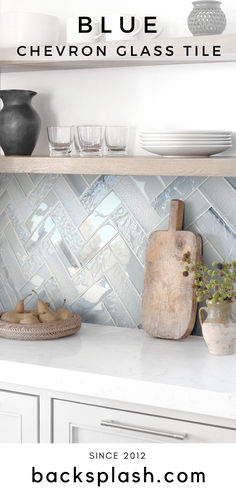 a kitchen counter with white cabinets and glass tiles on the backsplash above it