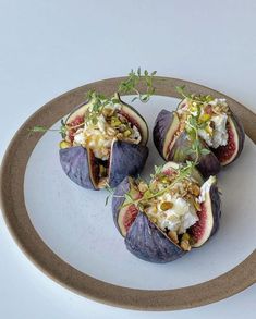 four figs on a plate topped with cheese and nuts