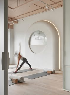 a woman is doing yoga in front of a circular mirror on the wall behind her