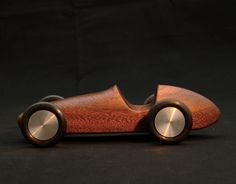 a wooden toy car sitting on top of a black surface