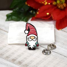 a pin with a santa clause on it sitting next to some christmas decorations and a poinsettia