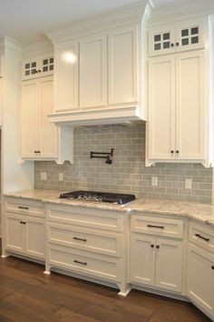 a kitchen with white cabinets and marble counter tops