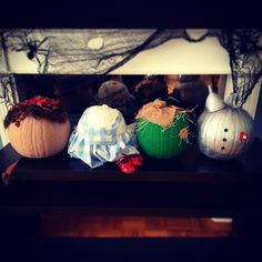 three pumpkins sitting on top of a black table next to a white and blue wall