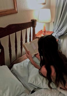 a woman laying in bed reading a book